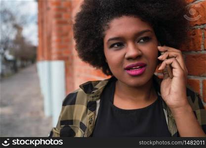 Portrait of Afro American latin woman talking on the phone outdoors in the street. Urban and communication concept.
