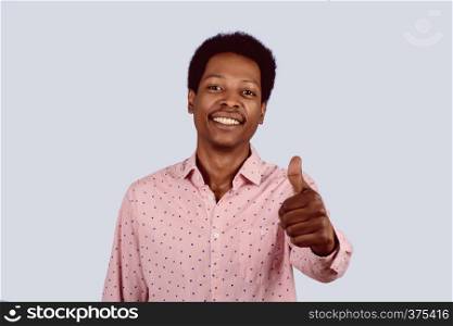 Portrait of Afro American man looking at camera showing thumbs up on studio.