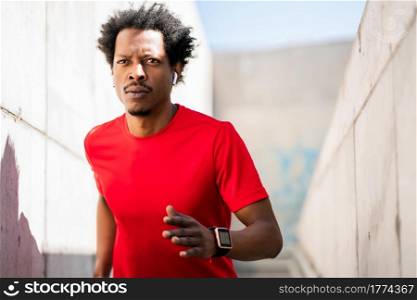 Portrait of afro athlete man running and doing exercise outdoors. Sport and healthy lifestyle.. Athletic man running and doing exercise outdoors.