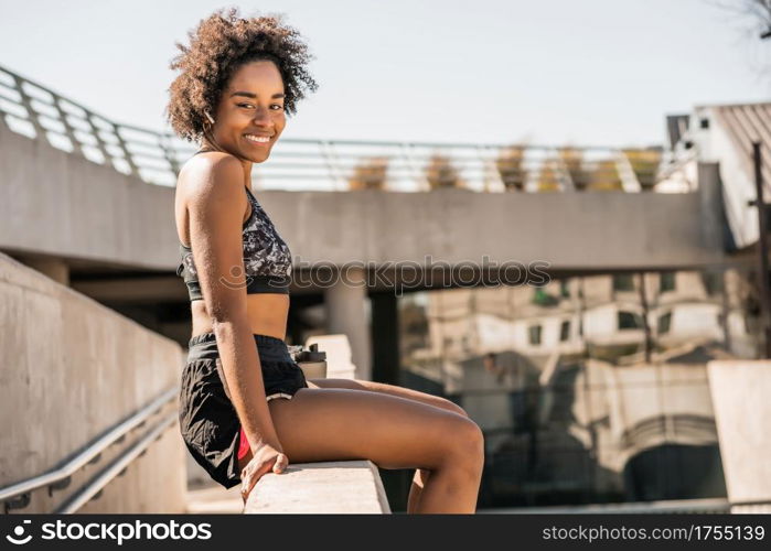 Portrait of afro athlete woman relaxing and sitting after work out outdoors. Sport and healthy lifestyle.