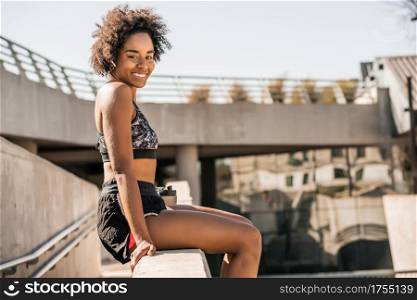 Portrait of afro athlete woman relaxing and sitting after work out outdoors. Sport and healthy lifestyle.