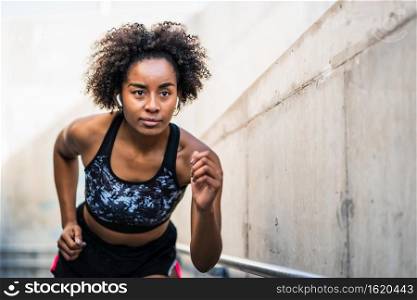 Portrait of afro athlete woman running and doing exercise outdoors. Sport and healthy lifestyle.