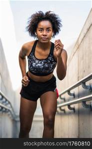 Portrait of afro athlete woman running and doing exercise outdoors. Sport and healthy lifestyle.