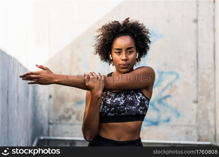 Portrait of afro athlete woman stretching arms before exercise outdoors. Sport and healthy lifestyle.