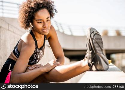 Portrait of afro athlete woman stretching legs before exercise outdoors. Sport and healthy lifestyle.