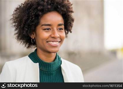 Portrait of afro business woman smiling while standing outdoors on the street. Business and urban concept.. Portrait of afro business woman outdoors on the street.