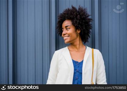 Portrait of afro business woman smiling while standing outdoors on the street. Business and urban concept.