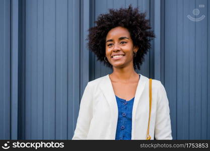 Portrait of afro business woman smiling while standing outdoors on the street. Business and urban concept.