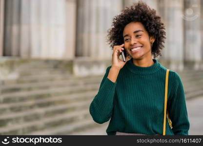 Portrait of afro business woman talking on the phone while standing outdoors at the street. Business and urban concept.