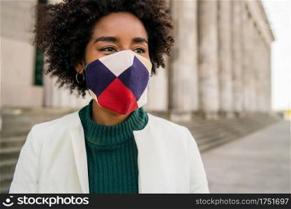 Portrait of afro business woman wearing protective mask while standing outdoors on the street. Business and urban concept.