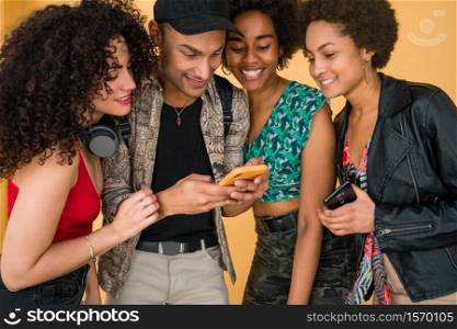 Portrait of Afro friends having fun in the city and spending good time together while using their mobile phone. Friendship and lifestyle concept.