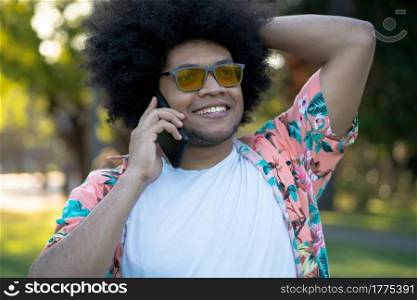 Portrait of afro latin man talking on the phone while standing outdoors on the street. Urban concept.