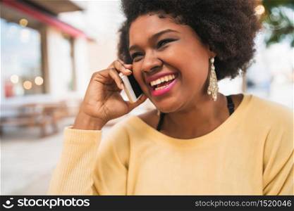 Portrait of Afro latin woman talking on the phone while sitting at coffee shop. Communication concept.