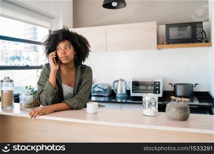 Portrait of afro woman talking on the phone with a cup of coffee at home. Communication concept.
