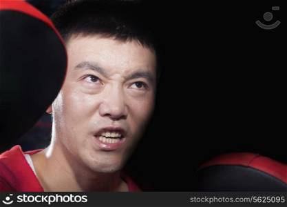 Portrait of aggressive looking boxing coach at the gym holding pads