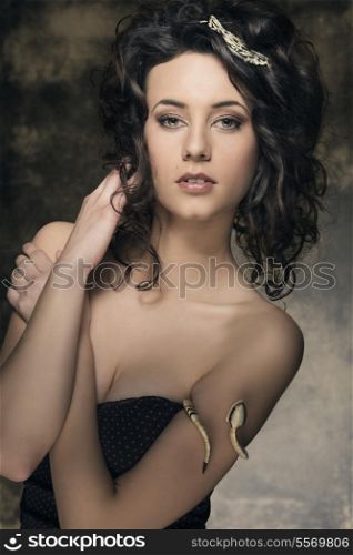 portrait of amazing brunette woman with sexy low-necked dress, creative jewels and cute curly hair-style. Fashion elegant portrait