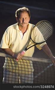 Portrait of an active senior man in his 70s on the tennis court.
