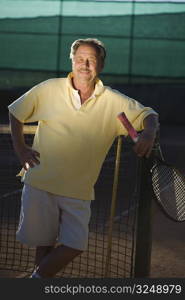 Portrait of an active senior man in his 70s on the tennis court.