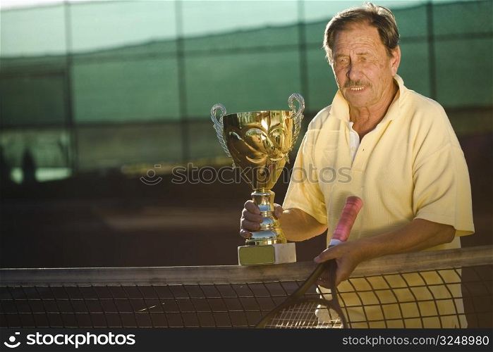 Portrait of an active senior man in his 70s on the tennis court.