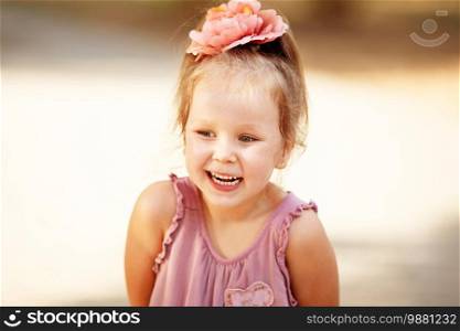 Portrait of an adorable preschool age girl with a hairpin with a flower on her head. Positive emitions. Happy child.