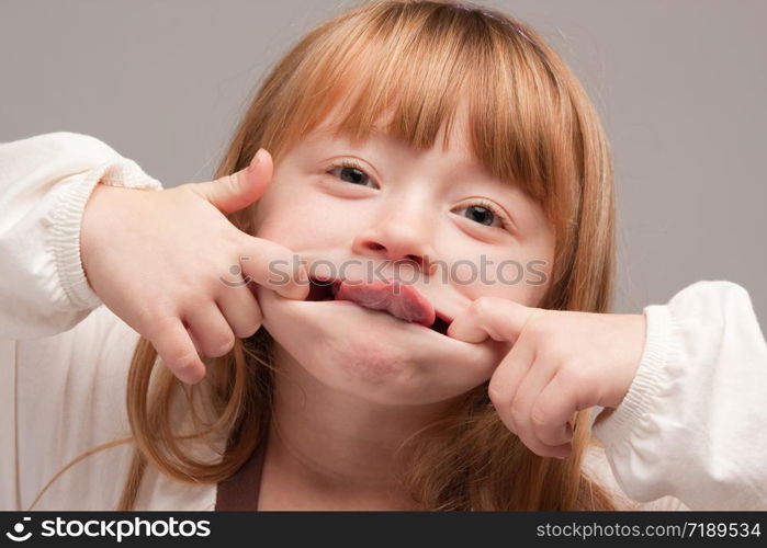 Portrait of an Adorable Red Haired Girl on a Grey Background.