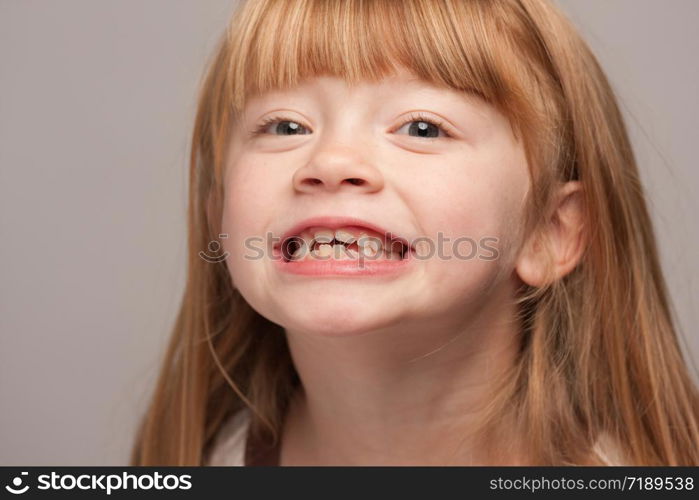 Portrait of an Adorable Red Haired Girl on a Grey Background.