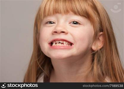 Portrait of an Adorable Red Haired Girl on a Grey Background.