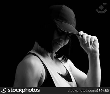 portrait of an adult girl with black hair holding a cap on her head, black and white toning