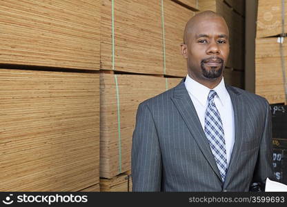 Portrait of an African American businessman standing in front of stacked wooden planks