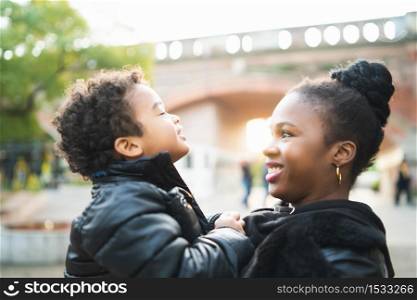 Portrait of an African american mother with his son playing together outdoors in the park and having fun. Monoparental family.