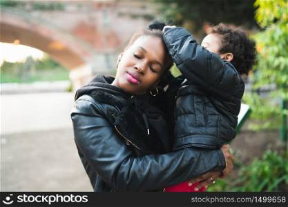 Portrait of an African american mother with his son standing outdoors in the park, having fun. Monoparental family.