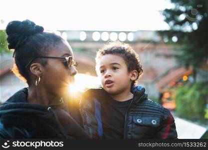 Portrait of an African american mother with his son standing outdoors in the park, having fun. Monoparental family.
