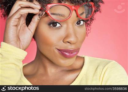 Portrait of an African American woman holding retro glasses over colored background