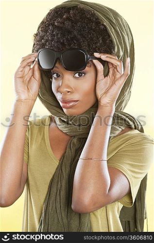 Portrait of an African American woman holding sunglasses with a stole over her head