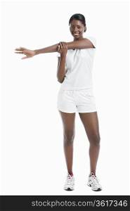Portrait of an African American young woman stretching arm over white background