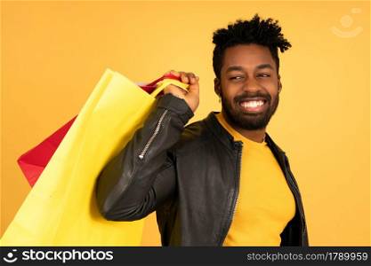 Portrait of an afro man smiling while holding shopping bags against isolated background. Shop concept.