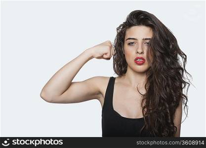 Portrait of an aggressive woman with punching gesture over gray background