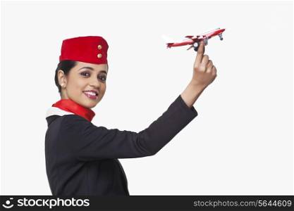 Portrait of an airhostess holding toy airplane isolated over white background