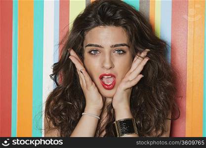 Portrait of an amazed young woman over colorful striped background