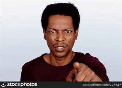 Portrait of an angry afro american man pointing at camera on studio. Emotions