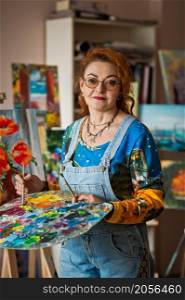 Portrait of an artist with a lot of experience on the background of the study.. An experienced artist works in her own studio 2901.