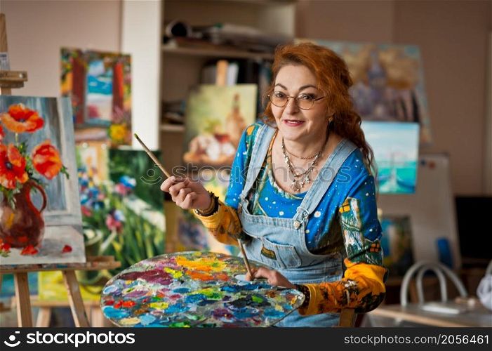Portrait of an artist with a lot of experience on the background of the study.. An experienced artist works in her own studio 2902.