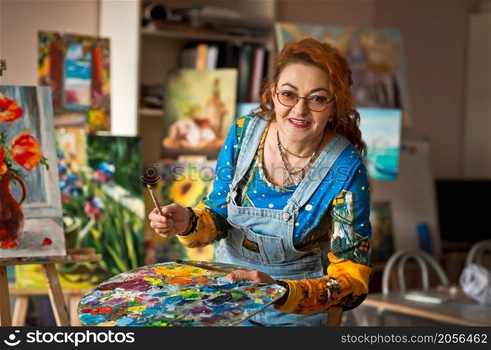 Portrait of an artist with a lot of experience on the background of the study.. An experienced artist works in her own studio 2903.