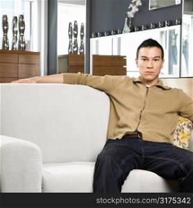 Portrait of an Asian male sitting on couch.
