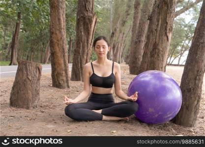 Portrait of an Asian woman meditating in yoga class club doing exercise and yoga at natural beach and sand outdoor in sport and recreation concept. People lifestyle activity.