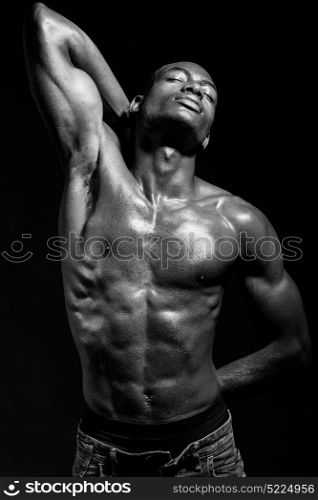 Portrait of an athletic black man on black background. Black and white