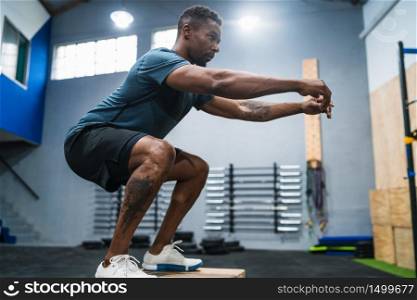 Portrait of an athletic man doing box jump exercise. Crossfit, sport and healthy lifestyle concept.