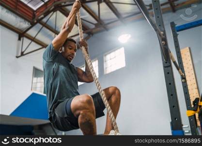 Portrait of an athletic man doing climbing exercise at the gym. Crossfit, sport and healthy lifestyle concept.