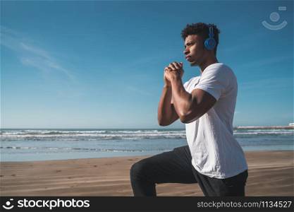 Portrait of an athletic man doing exercise at the beach. Sport and healthy lifestyle concept.