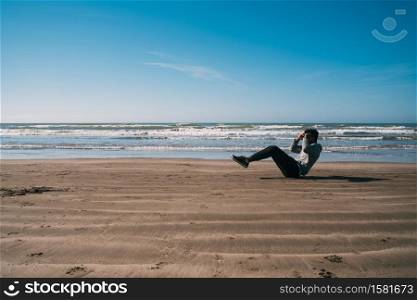 Portrait of an athletic man doing exercise at the beach. Sport and healthy lifestyle concept.